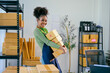© Parichat - Smiling african american female business owner carrying packages in her store