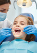 © W.O.W - Female dentist examining a little girl patient teeth for dental health. Pediatric dentistry care and oral examination.