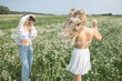 © Andrey_Arkusha - Two young girls photographer and model pose in a chamomile field