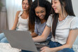 © Art_Photo - Diverse group of women friends smiling and talking while using laptop, browsing social media, shopping online, watching movies or series enjoying entertainment and connection digital lifestyle at home