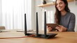 © Md Fazly Rabby - Selective focus at router. Internet router on working table with blurred happy woman using tablet at the background. Fast and high speed internet connection from fiber line with LAN cable connection.