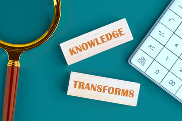 KNOWLEDGE TRANSFORMS concept words made of wooden blocks on a green background next to a calculator, top view