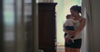 © Marco - Mother lovingly holding her baby while walking in a softly lit room, creating a peaceful moment of connection and caregiving in a warm home setting-SD 480p