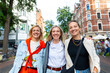 Three cheerful young adult women friend walk street old european german Hannover city street enjoy having fun laughing sunny day together. Female persons friendship celebration party weekend