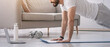 © Prostock-studio - Online lesson, new normal and covid-19 quarantine. Arabian bearded young guy doing push-ups, watches fit video at laptop, with dumbbells, bottle of water on floor in living room interior, side view