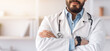 © Prostock-studio - Modern telemedicine, health care, therapist and doctor advice during lockdown. Serious confident attractive arabian guy in white coat, crossed arms on chest in office interior in clinic, free space