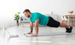 © Prostock-studio - Happy millennial european man doing plank or push ups on mat with laptop in living room interior, profile, copy space. Body care, sports blog, online lesson, workout at home during covid-19 lockdown