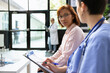 © DC Studio - Asian woman listening to healthcare worker during a checkup at a clinic, receiving a treatment plan and pills recommendation. Nurse reviews medical history and recovery steps for wellness.
