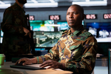 Army telecommunication systems professional using radio and satellite devices, providing combat support. Military unit managing communications networks, looking at displays