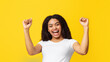 © Prostock-studio - Win concept. Overjoyed african american lady cheering and screaming, celebrating victory and shaking clenched fists on yellow studio background. Emotional overwhelmed lady yelling feeling happy