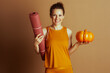 © Alliance - Smiling Woman with Yoga Mat and Autumn Pumpkin