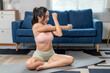 © Apichat - Young asian woman stretching arms at home on yoga mat
