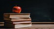 © Kalea - Rustic stack of old books with a red apple placed on top, against a dark chalkboard background, evoking education and knowledge