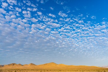 Wall Mural - Stunning desert landscape with scattered clouds in a bright blue sky, capturing the beauty of nature