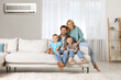 © New Africa - Happy family with children on sofa at home. Air conditioner keeping comfortable temperature in room