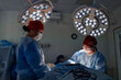 © Georgii - Surgeons operating in a sterile hospital room under bright surgical lighting