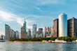 Manhattan skyline with waterfront view. Stunning Manhattan skyline overlooks the waterfront with boats and green spaces under a clear blue sky in New York.