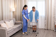 © Rakchanok - Young nurse assisting senior woman in walking with a walker, demonstrating caregiving, encouragement, and physical rehabilitation at home, healthcare, caregiver, medical, hospitality, recover.