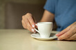 © leroy - Close up of female hands holding little white cup of tea or coffee.