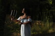 © Сергей Луговский - Young curly dark-haired woman in white dress with vintage candlestick in evening forest
