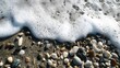 © Elegant Collections - White sea foam washing over colorful pebbles on a sandy beach ocean water