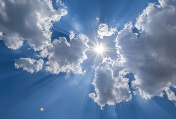 Wall Mural - Radiant sunlight beams through puffy white clouds against a vibrant blue sky, creating a heavenly and ethereal atmosphere
