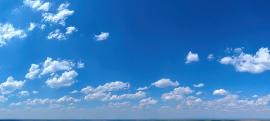 Wall Mural - Wide shot of a bright blue sky with fluffy white clouds scattered across the horizon. Horizon is blurred with land and ocean