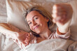 © Tatyana Gladskih - Happy middle aged woman sits on bed and stretching arms