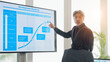 © metamorworks - A middle-aged male business person giving an explanation in front of a large screen monitor