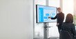 © metamorworks - A middle-aged male business person giving an explanation in front of a large screen monitor