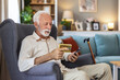 © Jelena Stanojkovic - Senior man, phone and reading medication on armchair for side effects or pharmaceutical instructions. Elderly, male or patient with pills on mobile smartphone for research or prescription at home.