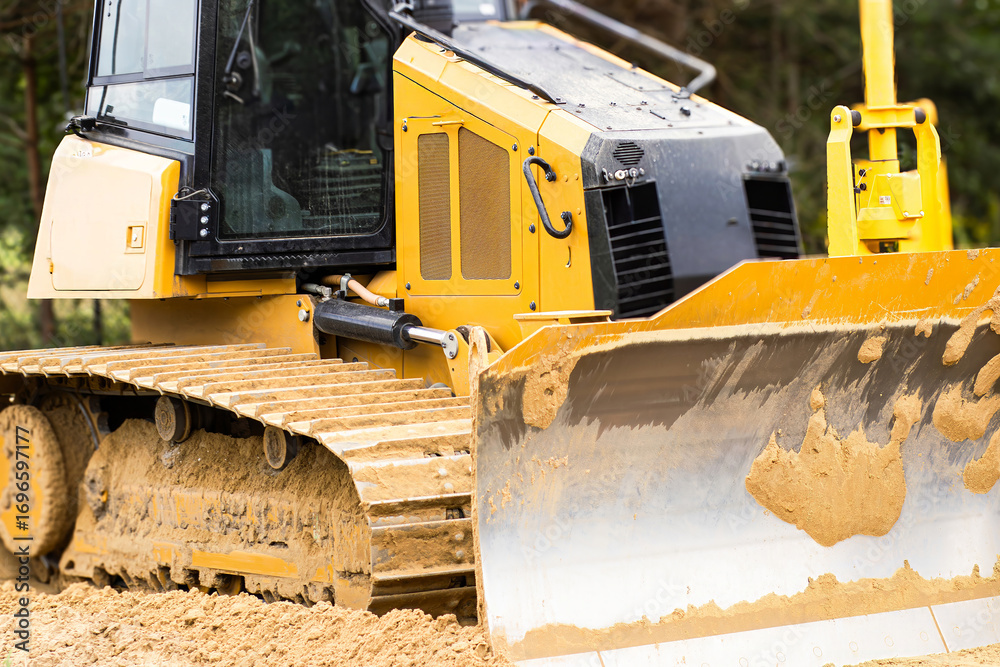 Heavy machinery bulldozer with yellow and black exterior is parked on a construction site, showcasing powerful tracks and blade, ready for earth-moving tasks