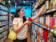 © Apichat - woman is shopping in a store and is holding a red jar