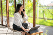 © Apichat - woman is sitting on a chair and talking on her cell phone