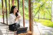 © Apichat - woman is sitting at a table with a laptop and a cell phone