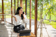 © Apichat - woman is sitting at a table with a laptop and a cell phone