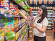 © Apichat - woman is shopping in a grocery store and is looking at a bag of chips