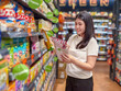 © Apichat - woman is shopping in a grocery store and is looking at a bag of chips