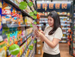 © Apichat - woman is shopping in a grocery store and is looking at a bag of chips