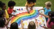 © Design - Diverse children collaboratively painting a vibrant rainbow on a large canvas