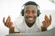© Louis-Paul Photo - Cheerful black man using headphone on sofa.
