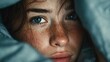 © SaroStock - Woman with freckles lies awake in bed early in the morning, looking thoughtful with soft lighting and focus on her beautiful features