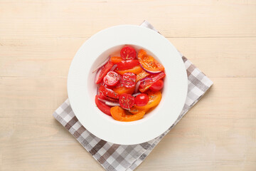 Wall Mural - Plate of fresh tomato salad with red onion on beige wooden background