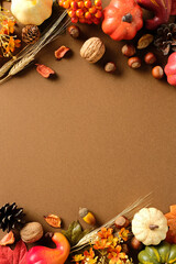 Wall Mural - Autumn border with pumpkins, pinecone, acorn, nut, wheat, leaf, berry and flower on brown background. Seasonal fall frame for Thanksgiving, greeting card or festive design