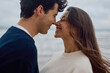 © we.bond.creations - Romantic couple rubbing noses on the beach, sharing a joyful moment of intimacy and connection against a beautiful ocean backdrop