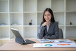 © Apichat - Asian businesswoman working with financial documents using tablet and calculator at office desk