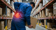 © Firyal Affina - Warehouse worker with acute lower back pain from lifting a box. Workplace injury and occupational health concept.