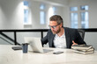© Volodymyr - Office workplace. Handsome business man working with laptop at desk in office. Businessman typing on keyboard, online business meeting. Businessman working in office. Office worker using laptop.