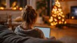 © Snowstudio - Young woman working on laptop in cozy living room during Christmas