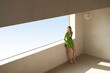 © Zhaofu - Woman in a vibrant green blazer standing by a large window in a modern minimalist setting.